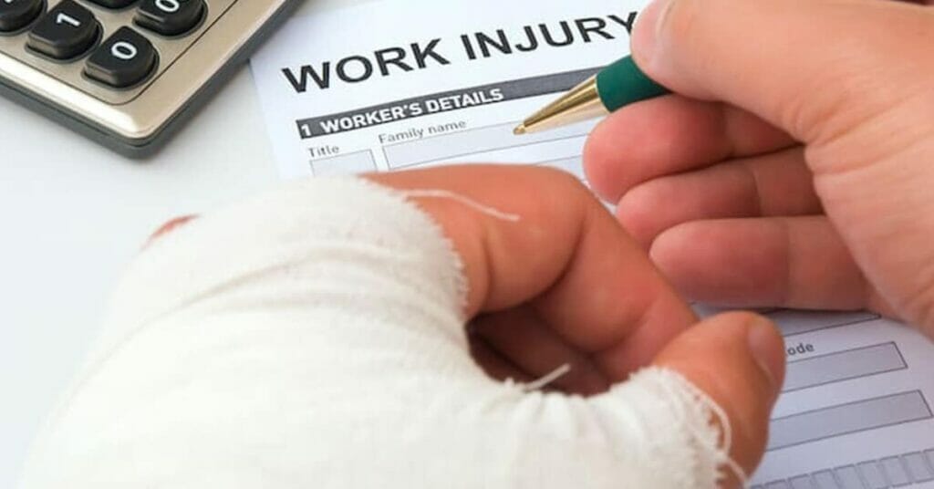 A person with a bandage on his hand is writing on a personal injury claim form.