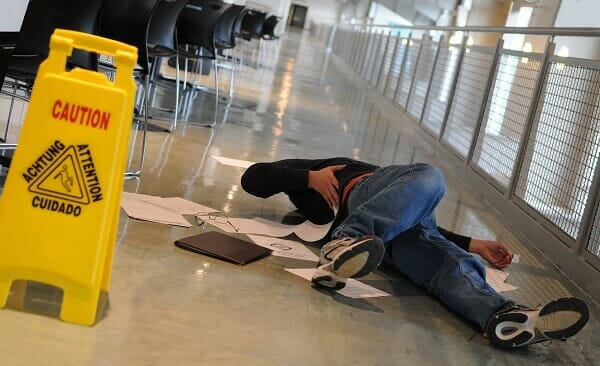         Description: A man laying on the floor next to a caution sign after an auto accident.