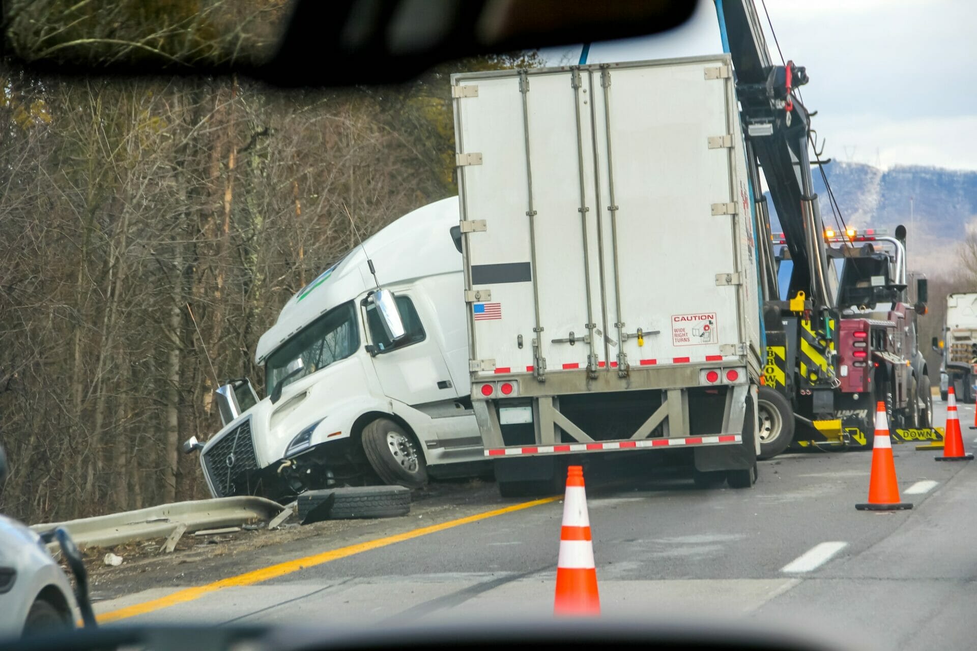 A semi truck involved in an auto accident on the side of the road.