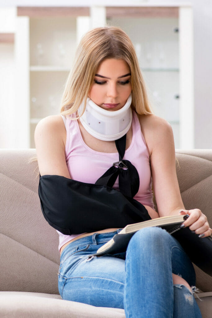 A woman sitting on a couch with a neck brace.