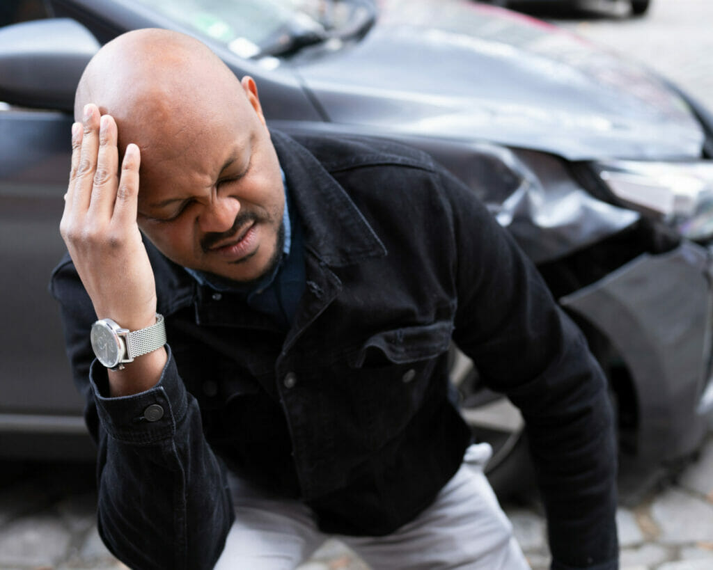 A man holding his head after a car accident.