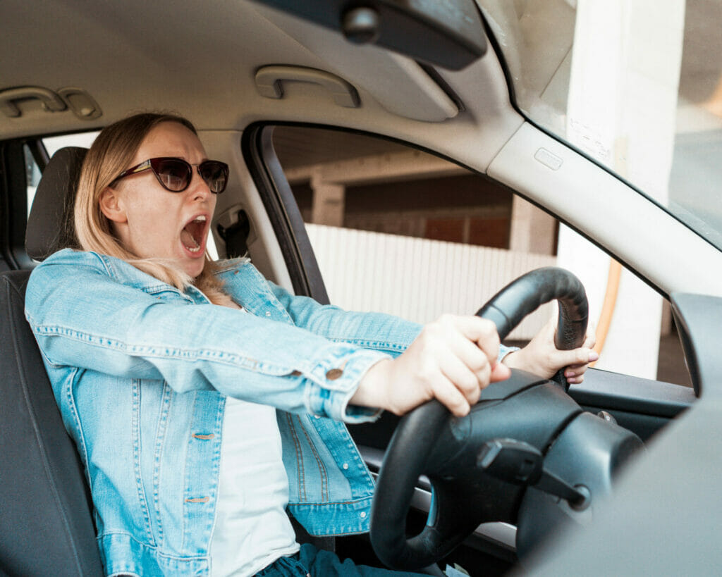 A woman yelling while driving a car.