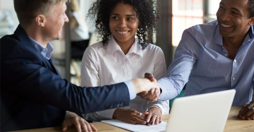 Three people at a table, seemingly closing a deal