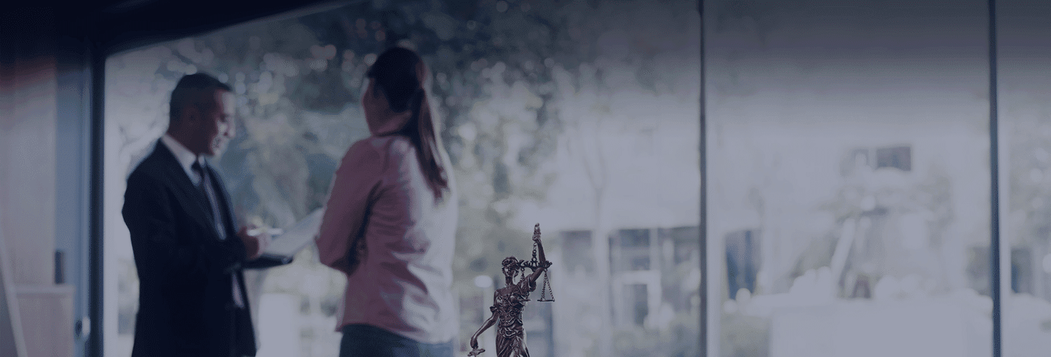 Two people converse in an office setting; one holds a clipboard, and a giraffe figurine is on a table